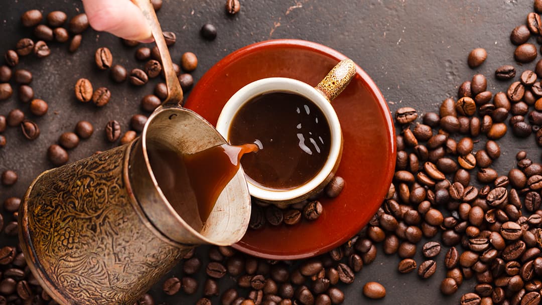 Una mano sirve café desde una jarra