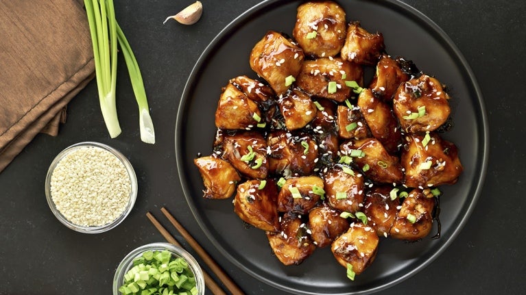 Plato con pollo teriyaki rodeado de vegetales y arroz crudo