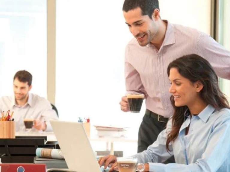 Compañeros de trabajo comentando asuntos y bebiendo café en la oficina