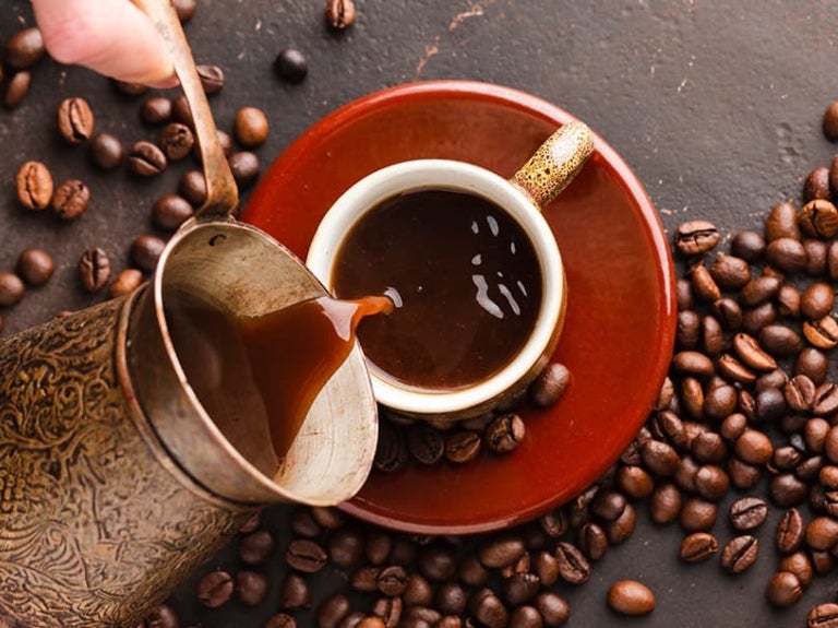 Una mano sirve café desde una jarra