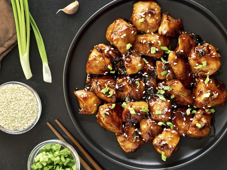 Plato con pollo teriyaki rodeado de vegetales y arroz crudo