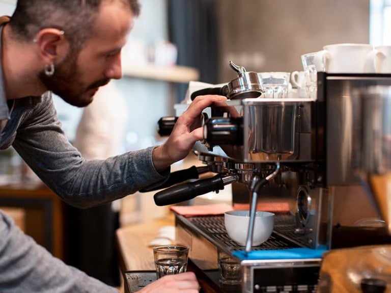 Camarero elaborando un café en máquina profesional